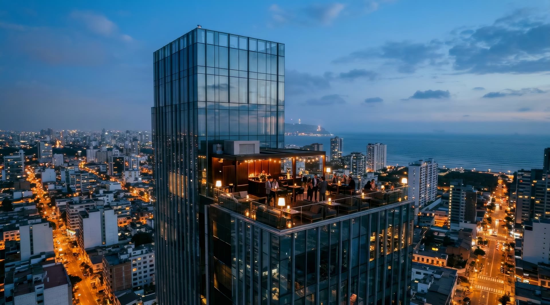 Torre de vidrio en Lima al anochecer con el sky bar iluminado en la azotea